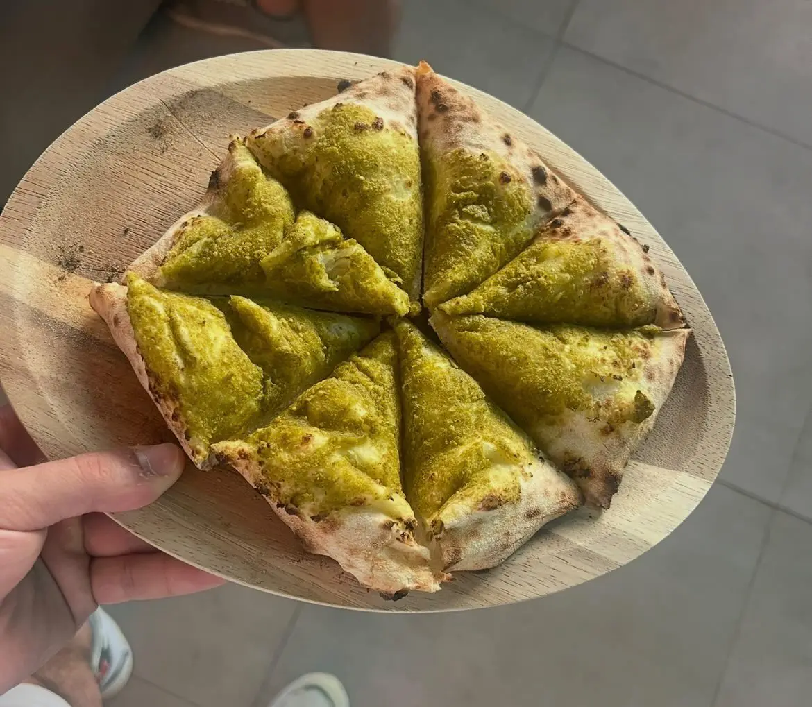 Sliced artisan flatbread topped with basil pesto on a wooden board