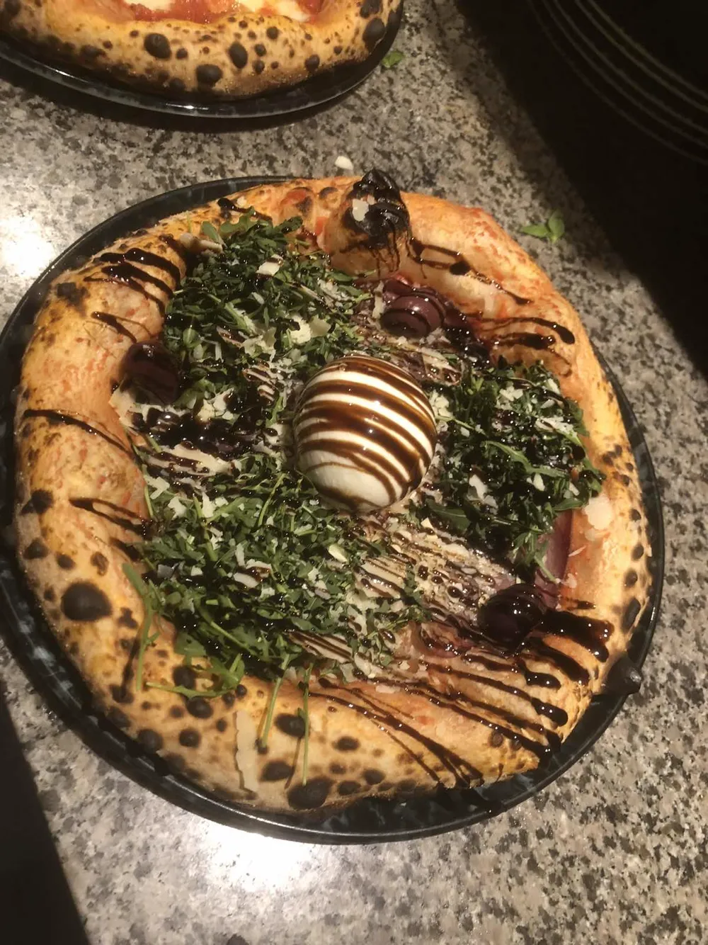 Pizza topped with burrata, rocket, shaved cheese and balsamic glaze