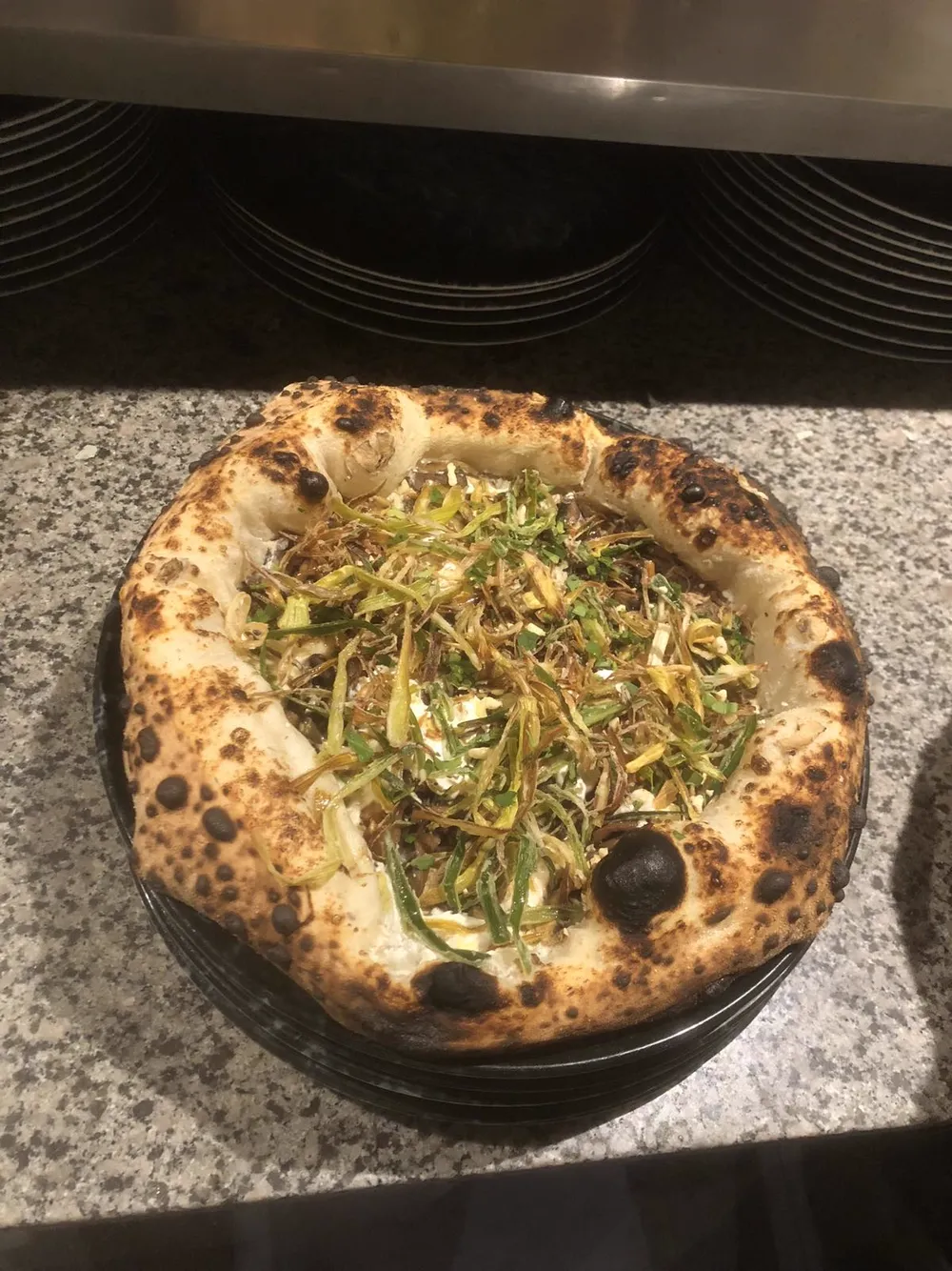 White pizza topped with soft cheese and crispy shredded leeks