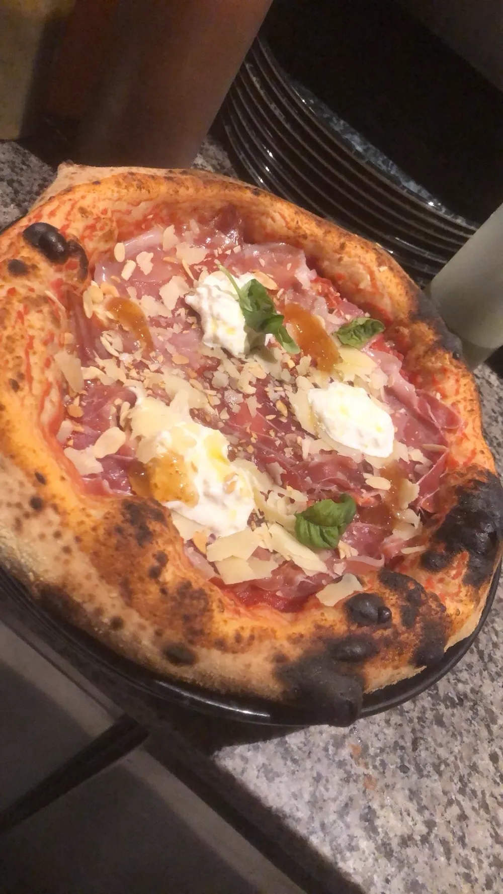 Pizza with prosciutto crudo, stracciatella, flaked almonds and fig jam