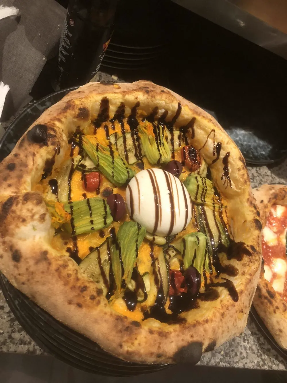 Fior Di Zucca and burrata pizza with roasted zucchini, zucchini blossom, red Datterino tomato, burrata, black Kalamata olives, balsamic glaze and extra virgin olive oil