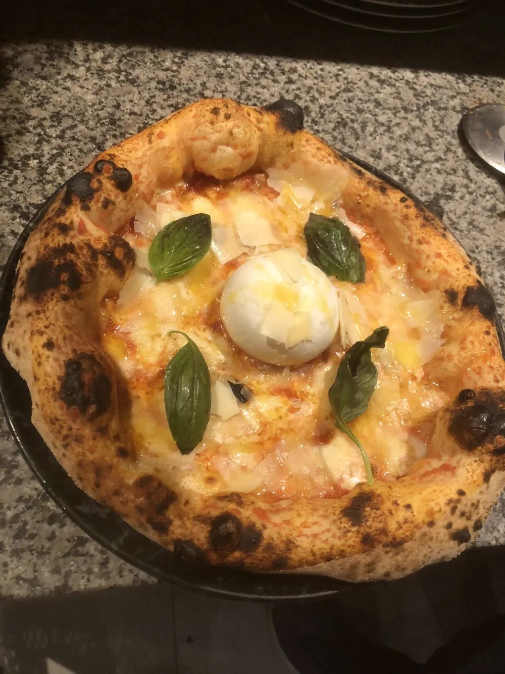 Neapolitan pizza with burrata in the centre and fresh basil leaves