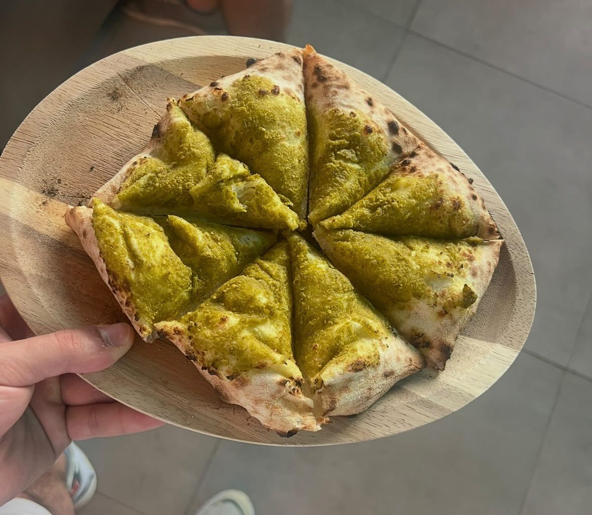 Sliced artisan flatbread topped with basil pesto on a wooden board